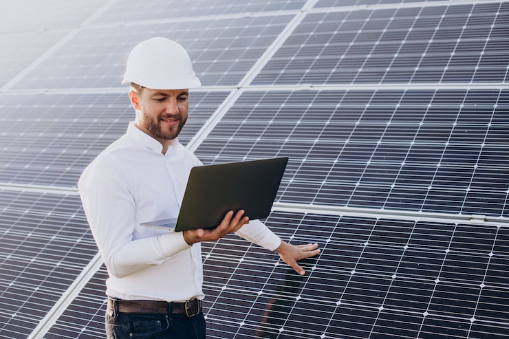 Jovem arquiteto ao lado de painéis solares fazendo diagnósticos no computador da placa de energia solar residencial