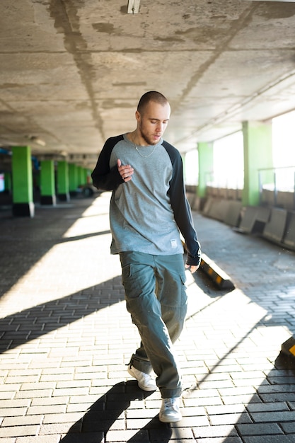 Jovem artista masculino dançando em um estacionamento com pilones