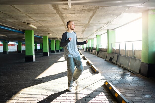 Jovem artista masculino dançando em um estacionamento com pilones