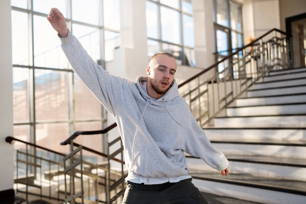 Jovem artista masculino dançando em um prédio ao lado de escadas