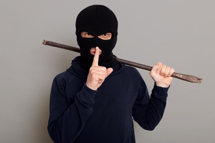 Foto grátis jovem assaltante vestido com um capuz preto e rosto mascarado