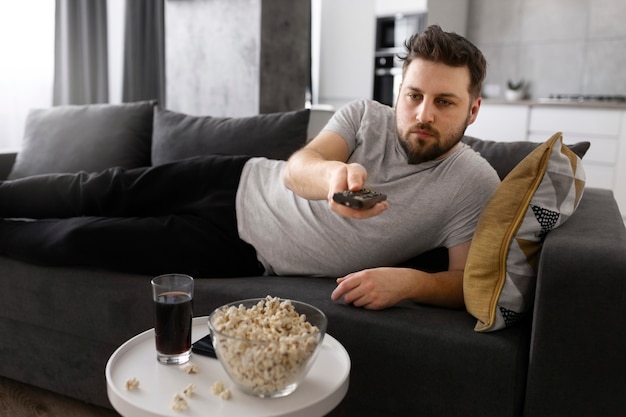 Jovem assistindo tv no sofá em casa