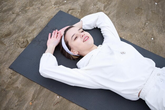 Jovem atleta bonita deitada no tapete na praia foto de alta qualidade