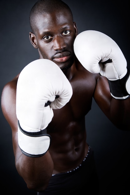 Jovem atleta boxer com luvas em fundo preto.