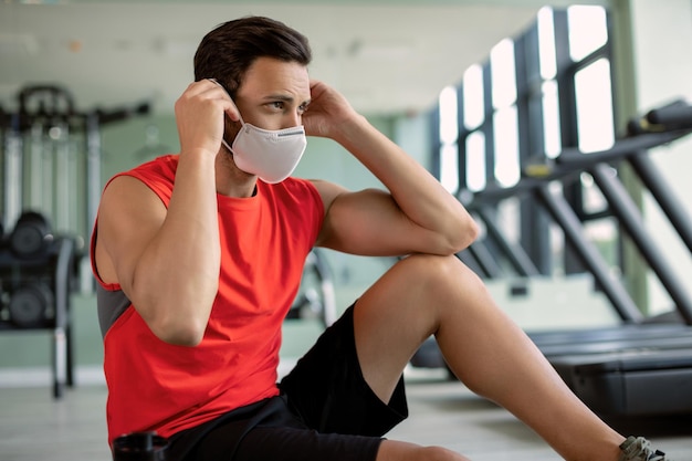 Foto grátis jovem atleta colocando máscara facial protetora antes do treinamento esportivo em uma academia