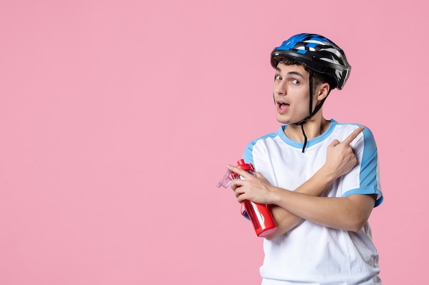 Jovem atleta de frente para o capacete com roupas esportivas e segurando uma garrafa de água