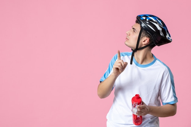 Jovem atleta de frente para o capacete com roupas esportivas e segurando uma garrafa de água