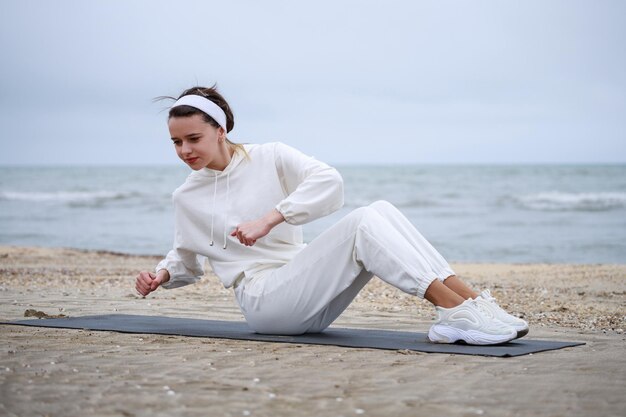 Jovem atleta feminina deitada no tapete e fazendo exercícios Foto de alta qualidade