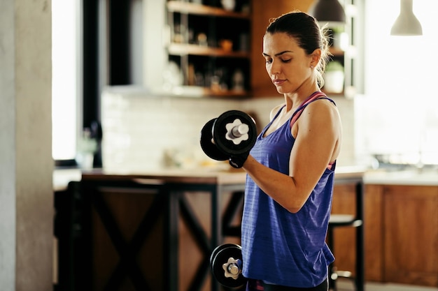 Jovem atleta feminina tendo treinamento esportivo em casa e levantando pesos