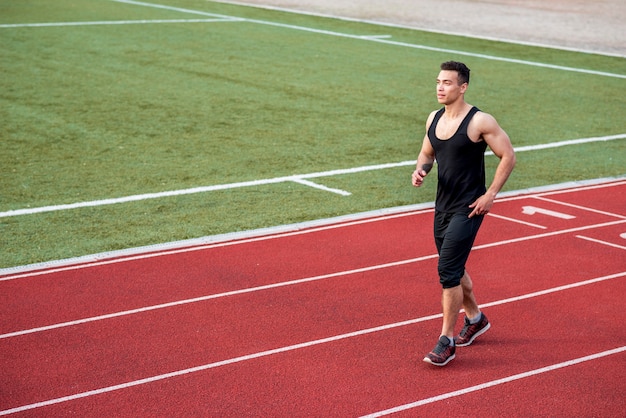 Jovem atleta masculino de aptidão correndo na pista de corrida