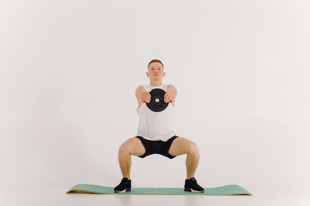 Jovem atlético fazendo exercícios em casa, homem fazendo treinamento, aquecimento antes do exercício de peso.