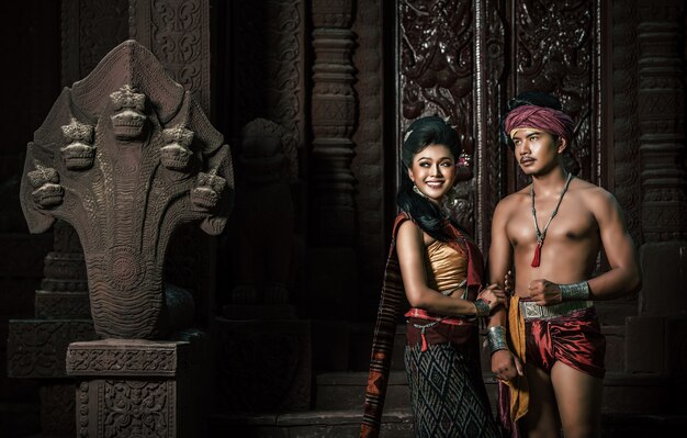 Jovem ator e atriz vestindo lindos trajes antigos, em monumentos antigos, estilo dramático. Interprete uma história popular de amor, lenda, um conto popular tailandês chamado "Phadaeng e Nang-ai" em um local antigo