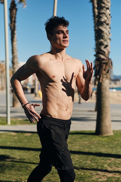 Foto grátis jovem atraente desportivo correndo pelas ruas. cara apto se aquecendo antes de treinar ao ar livre