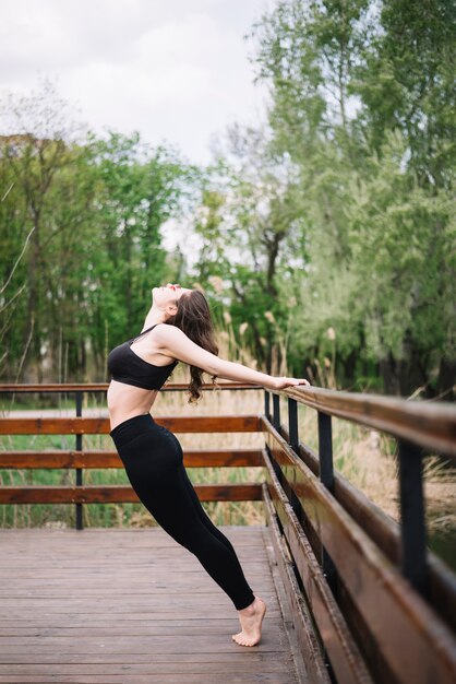 Jovem atraente, fazendo backbend em trilhos de madeira