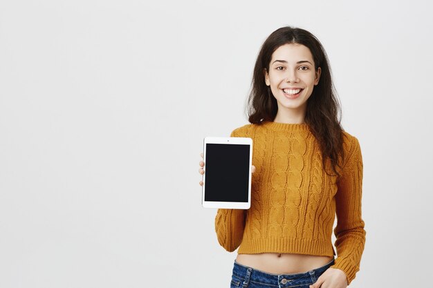 Jovem atraente feliz mostrando a tela do tablet digital