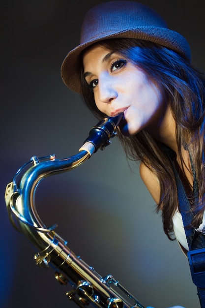 Jovem, atraente, mulher, chapéu, tocando, saxofone