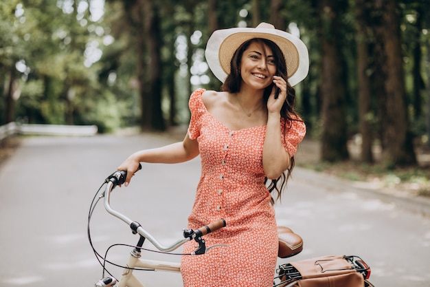 Jovem atraente num vestido de bicicleta e usando o telefone