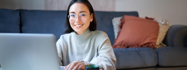 Foto grátis jovem autônoma sorridente freelancer que fica em casa trabalhando remotamente usando laptop