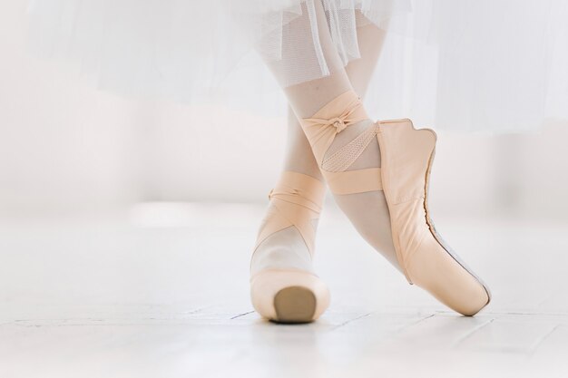 Jovem bailarina, closeup nas pernas e sapatos, em pé na posição de ponta.