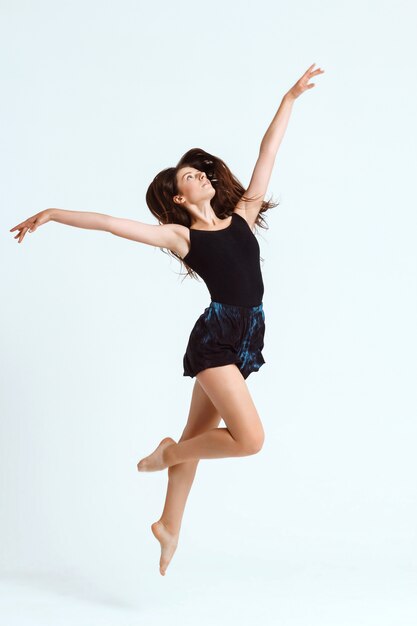 Jovem bailarina contemporânea linda posando sobre parede branca. Copie o espaço.