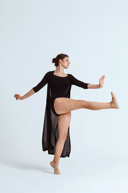 Jovem bailarina contemporânea linda posando sobre parede branca. Copie o espaço.