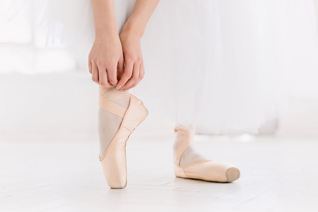 Jovem bailarina dançando, closeup nas pernas e sapatos, em pé na posição de ponta.