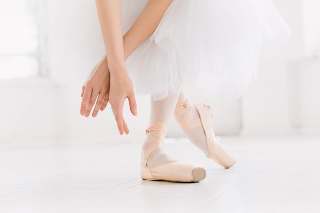 Jovem bailarina dançando, closeup nas pernas e sapatos, em pé na posição de ponta.