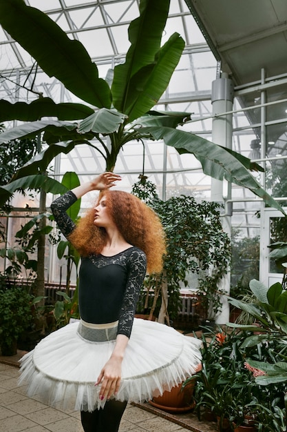 Jovem bailarina dançando em um jardim botânico dentro de casa