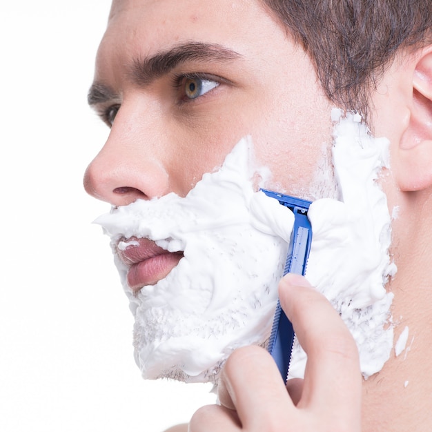 Foto grátis jovem barbeando a barba com a navalha