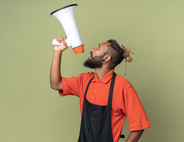 Jovem barbeiro afro-americano de uniforme olhando para cima, falando pelo palestrante