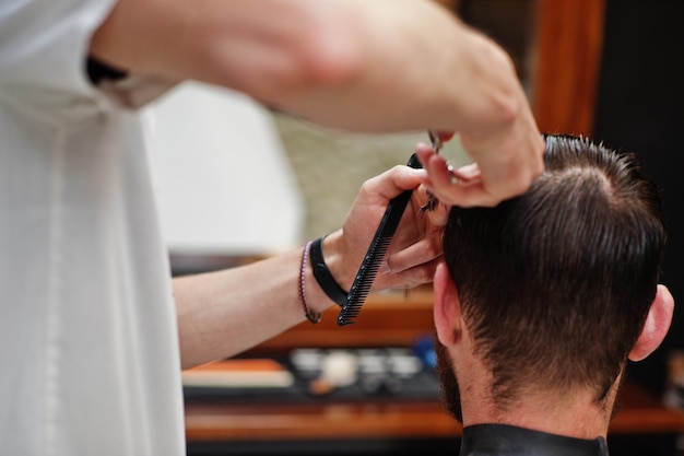 Foto grátis jovem barbudo cortando o cabelo pelo cabeleireiro enquanto está sentado na cadeira na barbearia barber soul