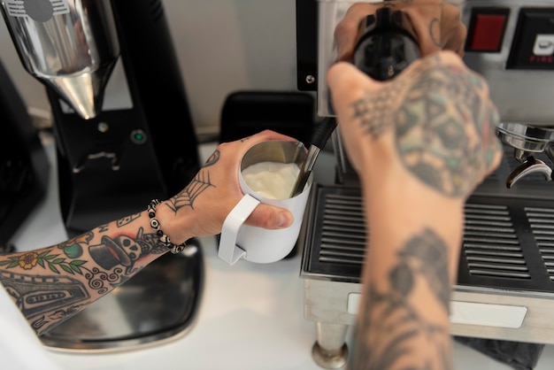 Jovem barista com tatuagens usando a máquina de café no trabalho
