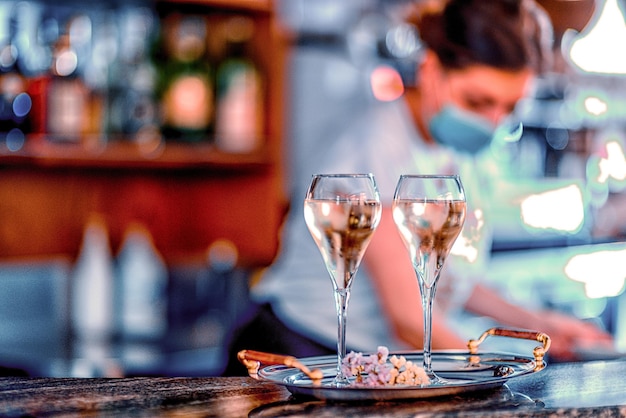 Jovem barman usando máscara facial derramando branco espumante