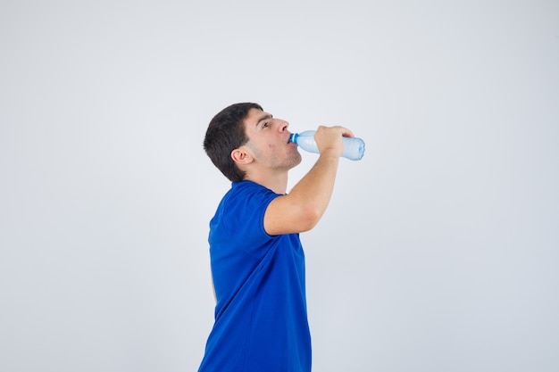 Jovem bebendo água em t-shirt e parecendo com sede. .