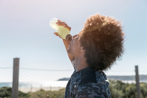 Jovem beber água de garrafa de plástico