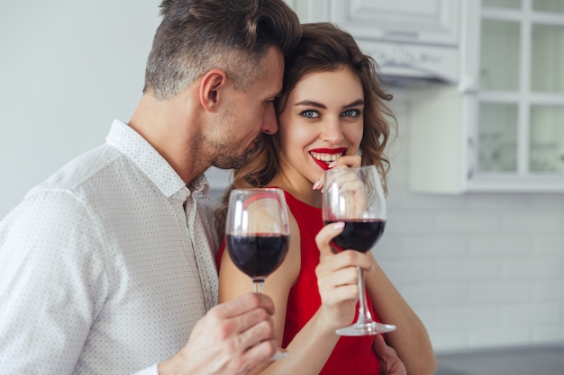 Foto grátis jovem beija sua bela mulher sorridente enquanto bebe vinho