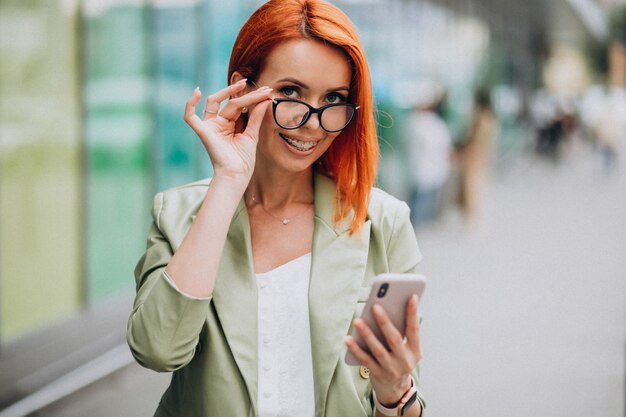 Jovem bela mulher bem sucedida no terno verde falando ao telefone