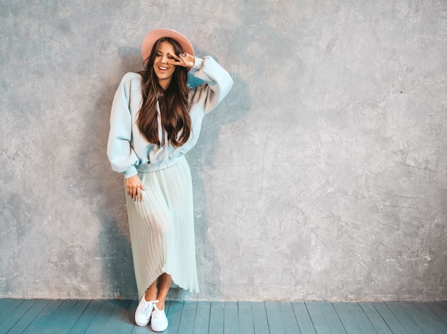 Jovem bela mulher sorridente olhando. Menina na moda em roupas de verão casual capuz e saia.