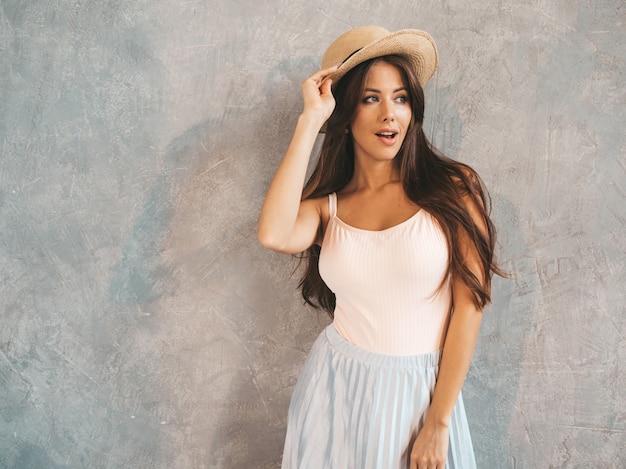 Jovem bela mulher sorridente olhando. Menina na moda em verão casual vestido e chapéu.