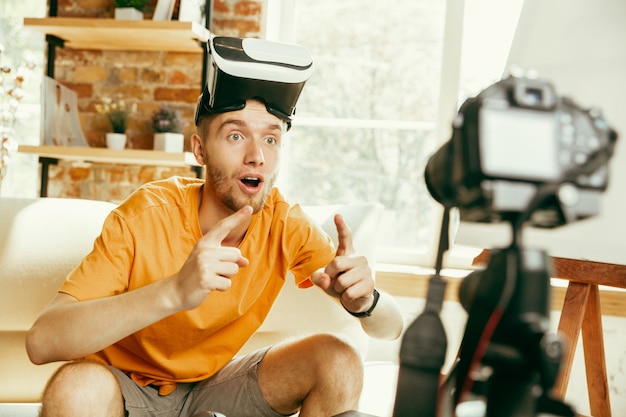 Jovem blogueiro caucasiano com equipamento profissional gravando análise de vídeo de óculos de realidade virtual