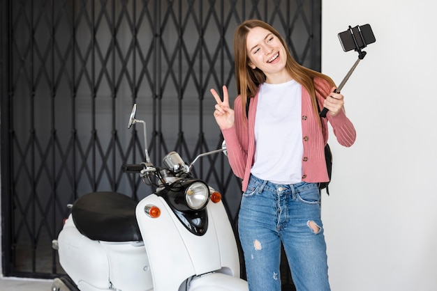 Foto grátis jovem blogueiro gravando-se ao lado de moto