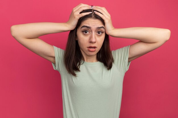 Jovem, bonita, caucasiana, impressionada, colocando as mãos na cabeça