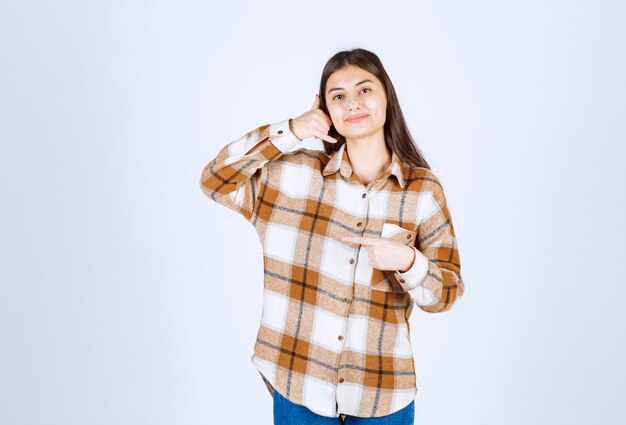 Jovem bonita fazendo gestos na parede branca.