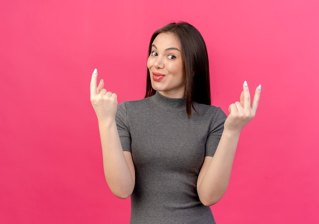 Jovem bonita impressionada mostrando um e dois com as mãos isoladas em um fundo rosa com espaço de cópia