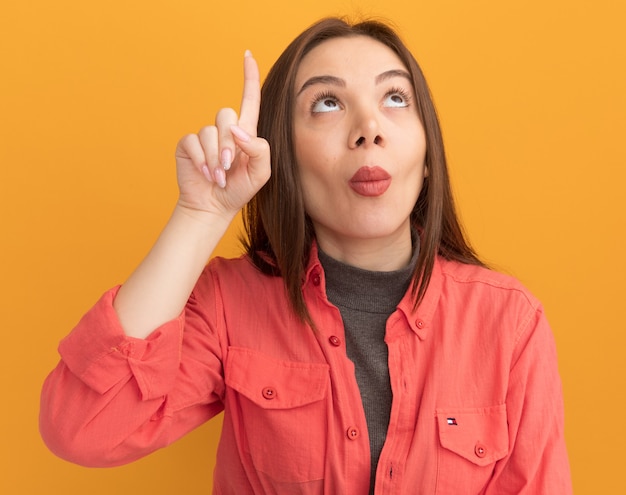 Foto grátis jovem bonita impressionada olhando e apontando para cima