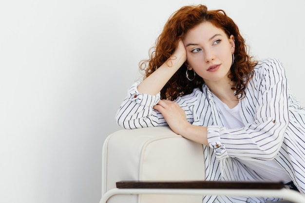 Jovem bonita mulher ruiva sentada no sofá na sala de estar