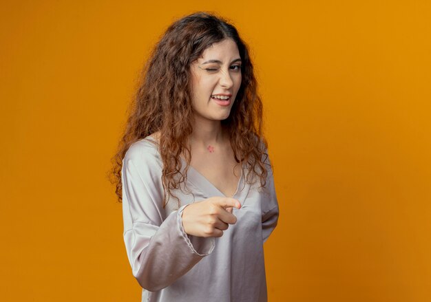 Jovem bonita piscando com pontos isolados na parede amarela