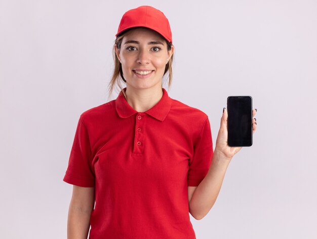 Jovem, bonita, satisfeita, entregadora de uniforme, segurando o telefone em branco