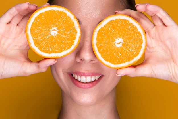 Foto grátis jovem bonita segurando fatias de laranja