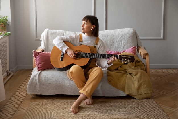 Jovem bonita tocando violão dentro de casa